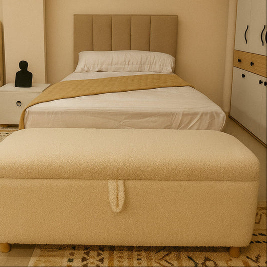 Beige upholstered bed with matching ottoman in a bedroom setting.
