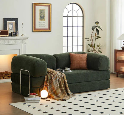 Green sofa in a living room with decorative items and a fireplace.