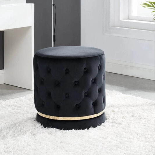Black tufted stool with gold band on a white rug in a room setting
