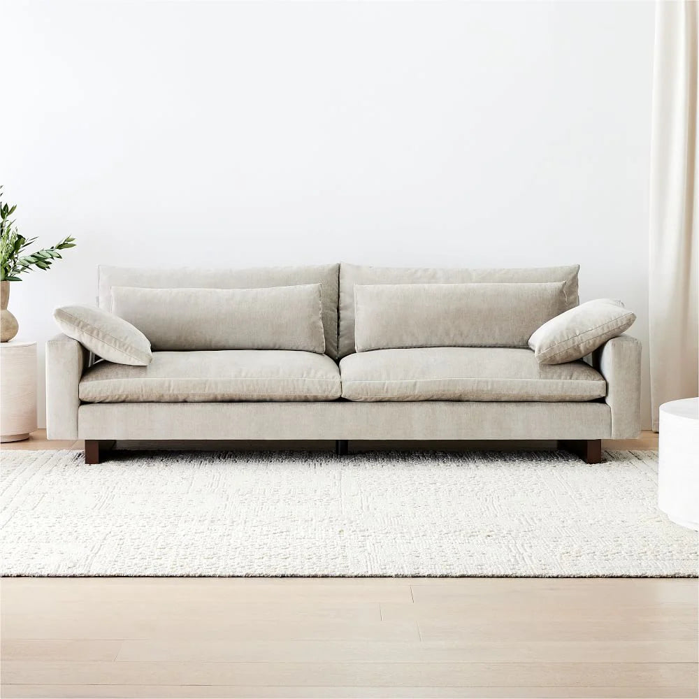 Beige sofa in a minimalistic living room with white walls and a white rug.