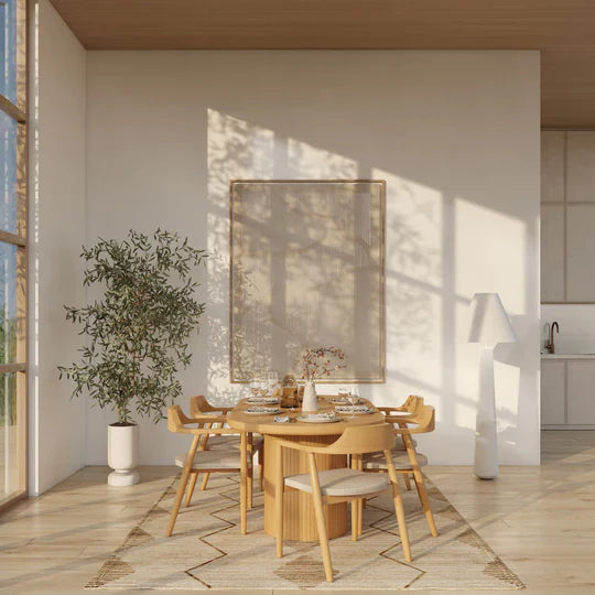 Modern dining area with wooden table and chairs, large mirror on the wall, and plant decoration.