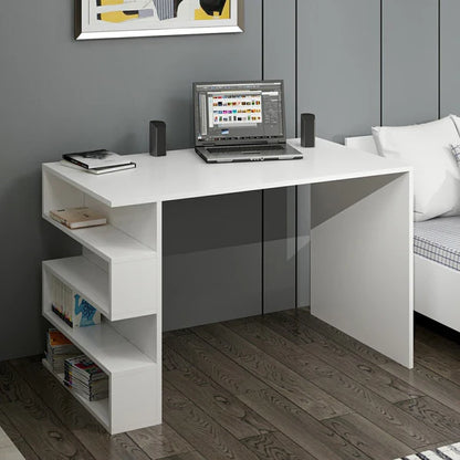 White L-shaped desk with a laptop, speakers, and books in a room with a gray wall and wooden floor.