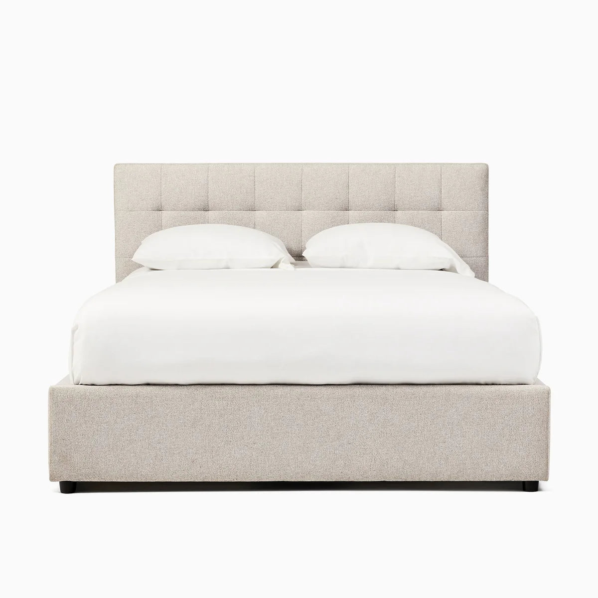 Beige upholstered bed with white bedding on a white background