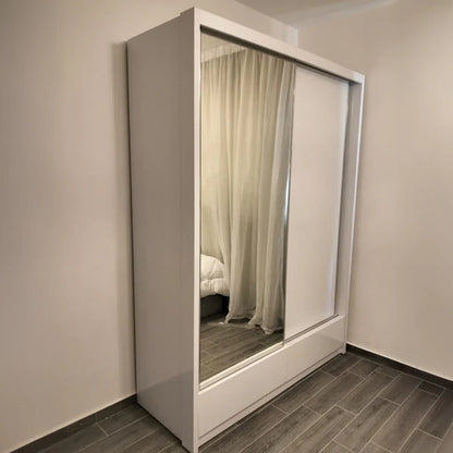 White wardrobe with a mirror reflecting a bedroom with curtains.