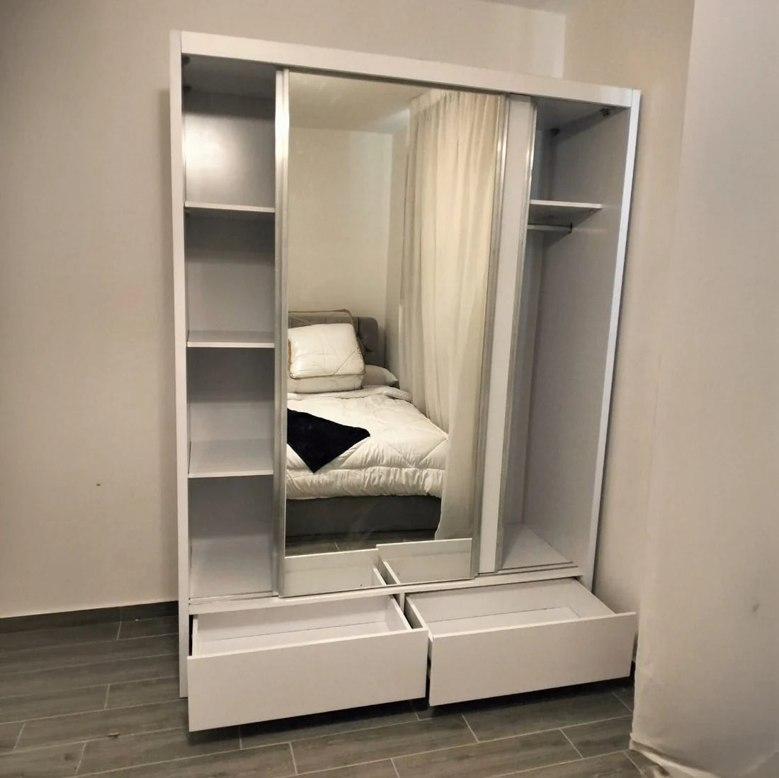 White wardrobe with mirror and drawers in a bedroom setting