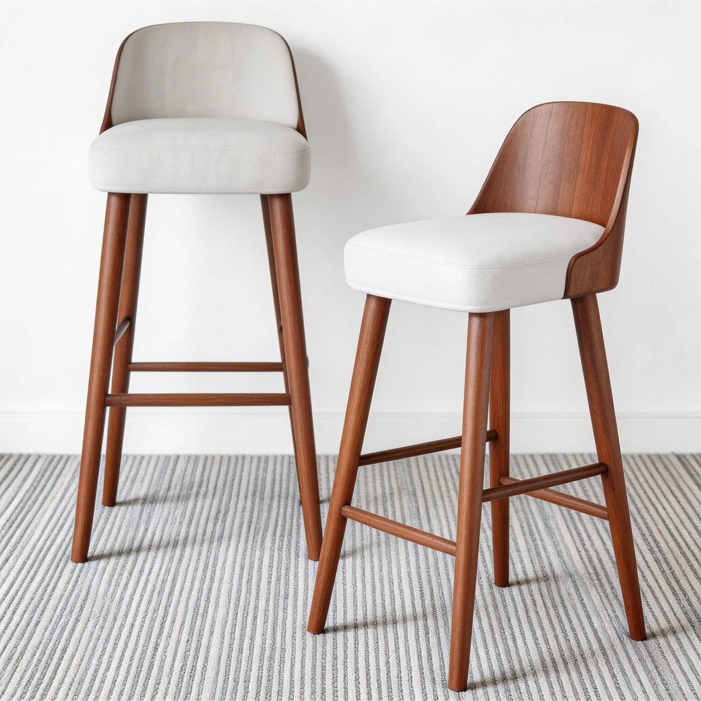 Two bar stools with wooden legs and white seats on a neutral background