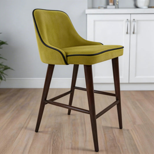 Green bar stool with wooden legs in a room with white cabinets and a plant.