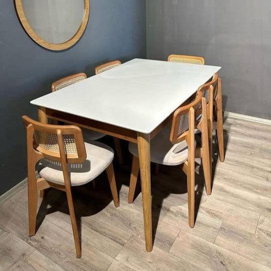Dining table set with chairs in a room with gray walls and wooden flooring.