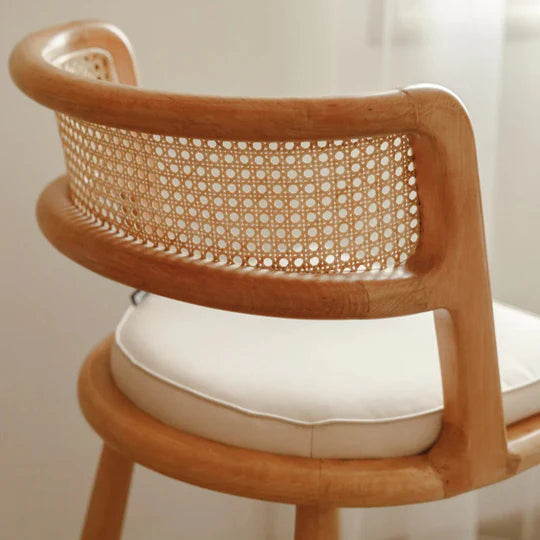 Wooden chair with wicker backrest and white cushion on a plain background
